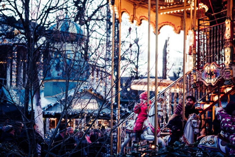 Ein gut besuchter Adventmarkt mit einem Pferdekarussell mit Kindern darauf