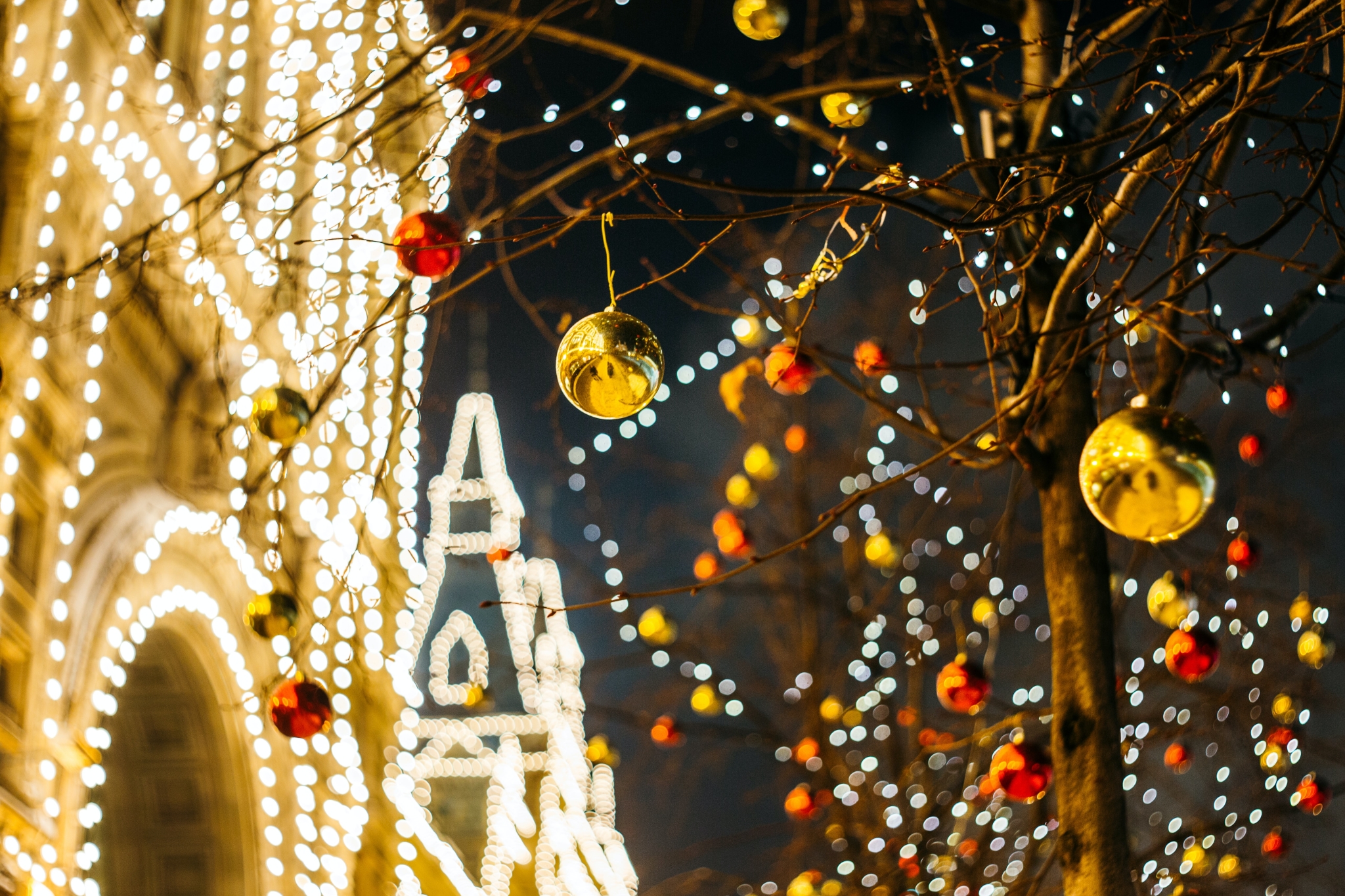 Christbaumkugeln und Lichterketten dekorieren Bäume und die Gebäude im Hintergrund