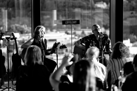 Löffelzart spielt mit Gitarre und Bass vor Publikum beim Artists’ Place in der hu:goes14 Rooftop-Bar in Salzburg.