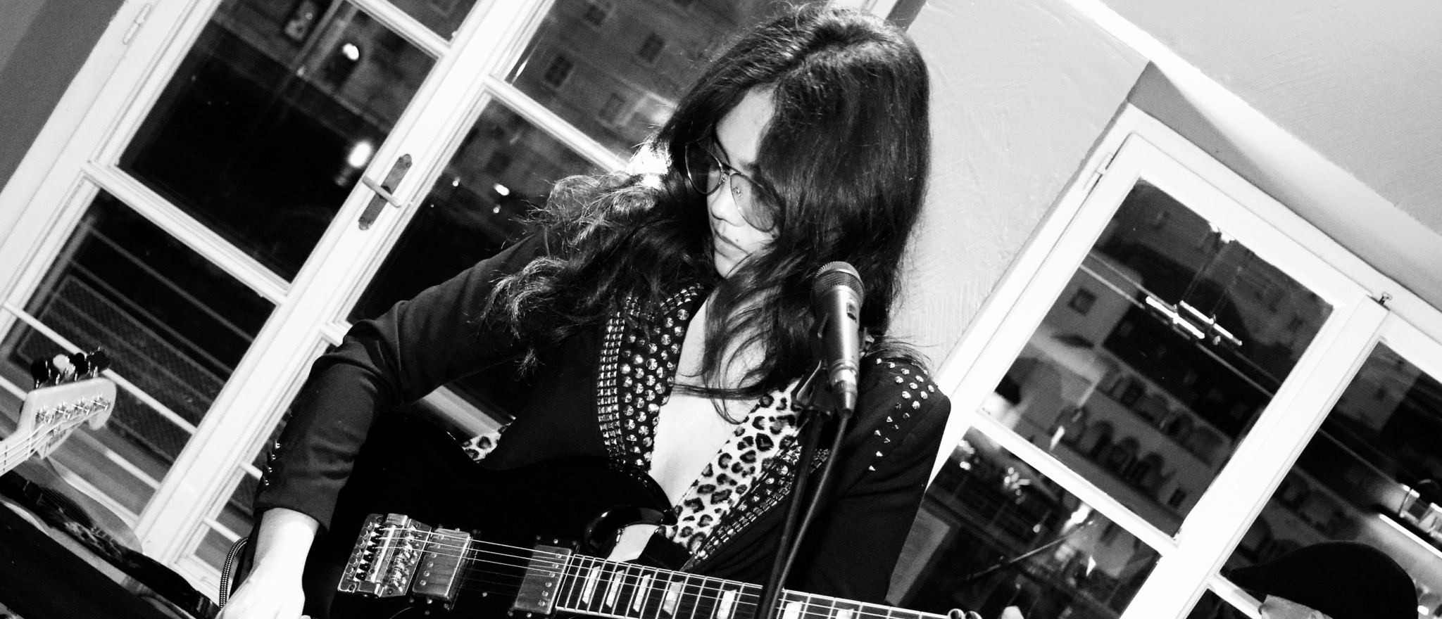 Mariana Isnenghi playing electric guitar during a live concert with her band.